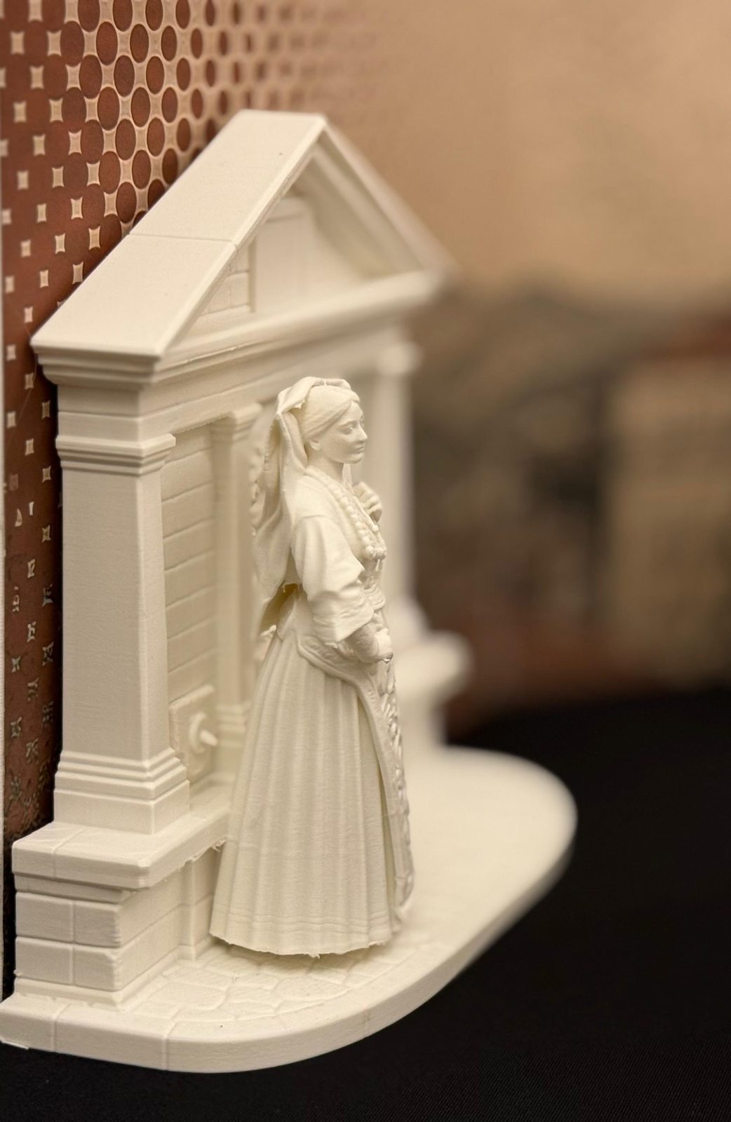 Alla Fontana del Borgo — donna in costume aviglianese davanti alla fontana con lo stemma civico, rilievo effetto gesso