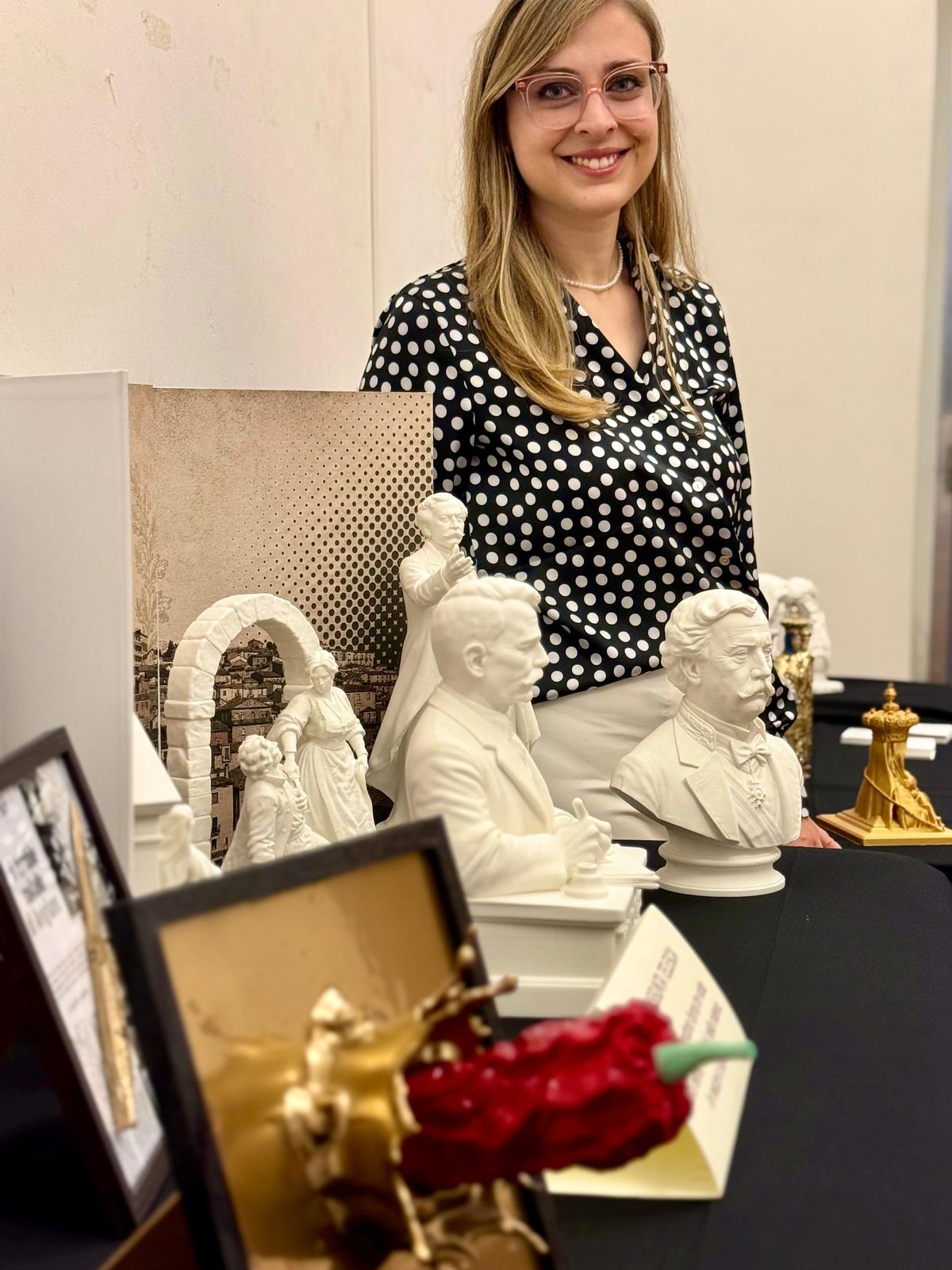 Mariassunta Telesca al suo tavolo espositivo, tra le sue sculture e i suoi rilievi